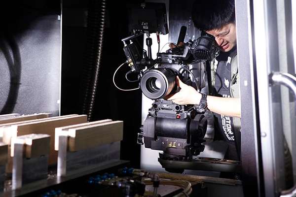 摄影师聚精会神的展示本领；拍摄吉他加工环境；